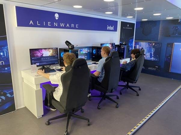 Three students sitting at games consoles inside the Dell Alienware truck, facing away from the viewer.